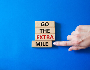 Go the extra mile symbol. Wooden blocks with words Go the extra mile. Businessman hand. Beautiful blue background. Business and Go the extra mile concept. Copy space.