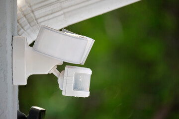 Motion sensor with light detector mounted on exterior wall of private house as part of security...