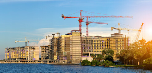 Naklejka premium Tower lifting cranes at high residential apartment buildings construction site. Real estate development