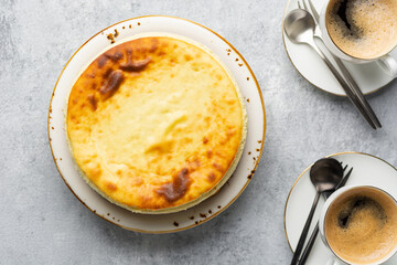 Breakfast concept. Top view of acottage cheese casserole with cups of coffee on a concrete light gray background. Coffee break with cheesecake.