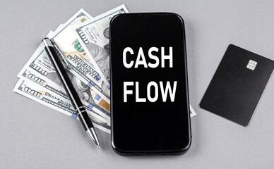 Credit card and text CASH FLOW on smartphone with dollars and pen. Business concept