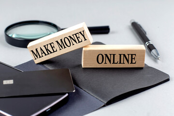 Fototapeta premium MAKE MONEY ONLINE text on wooden block on black notebook , business concept