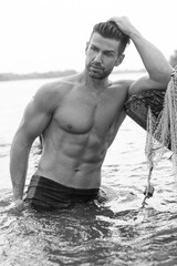 Handsome model with perfect body in sensual black and white photo shoot.