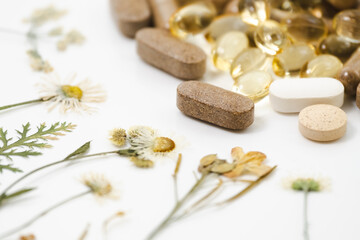 Medicinal capsules with dried medicinal herbs on white background. Herbal medicine, homeopathy, alternative medicine, organic pharmacy concept. Naturopathy and dietary supplement. Herbal plants