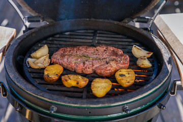 grilling at a sunny winter day -  a grilled steak with potaoes,  onions and rosemary from a outdoor...