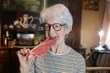 Senior woman eating a raw steak 