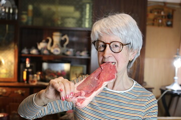 Senior woman eating a raw steak