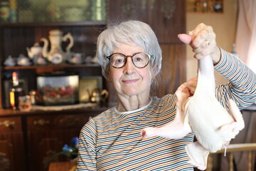 Senior woman holding a whole raw chicken  