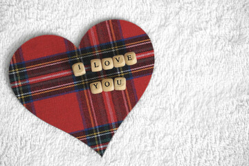 I love you letters on the red tartan patterned heart on the light background