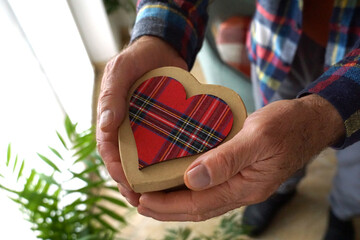 Heart-shaped gift box in the hands of an old man