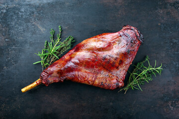 Traditionelle gegrillte Rehkeule mit Kräutern als Draufsicht auf einem rustikalen schwarzen Board mit Textfreiraum © HLPhoto