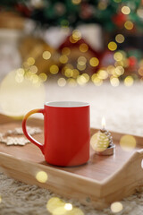 Obraz na płótnie Canvas Red mug on the background of the xmas tree bokeh lights. Christmas time, New Year holiday.