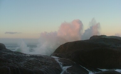 wave crashing over rocks at dusk