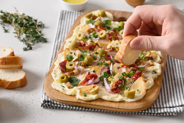 Homemade viral trendy Butterboard with onion, garlic, orange, herbs , crispy baguette and toasts on white background. Close up. Mens hand spreads bread.