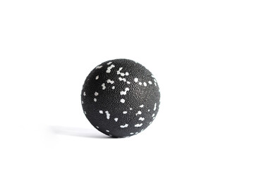 Massage black ball with white spots for trigger points isolated on a white background. Concept of myofascial release. Copy space.