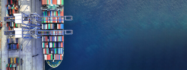 Aerial drone ultra wide top down photo of industrial cargo container ship being loaded by large...