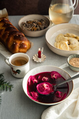 Obraz na płótnie Canvas Essential Ukrainian Christmas Eve supper dishes - borsch with vushka (porcini dumplings), varenyky, kutia, uzvar on linen tablecloth. 
