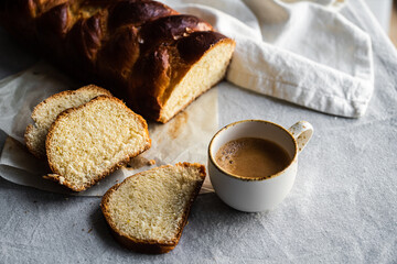 Slice of homemade braided bread and cup of espresso coffee on linen tablecloth. 