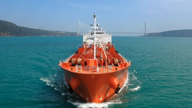 Bow and front deck of oil products tanker on ride. Supertanker loaded with full of oil underway in the open sea. Red prow, upper deck, pipe lines and winches of tanker ship cruising in ocean. Slow Mo.