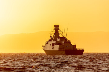 Turkish warship anchored in Izmir Bay in the setting sun with the mountains in the background