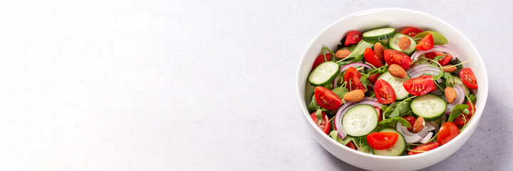 Healthy salad with spelt, oranges, pomegranate seeds. greens and nuts on light background, minimal style