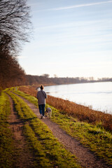 junge Frau geht mit Dalmatiner (Hund) an Fluss (Rhein) spazieren