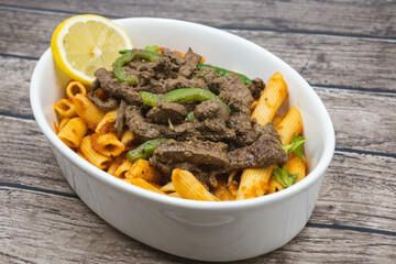 Pasta with red sauce and liver - a popular Egyptian dish - photographed at an oblique angle on a wooden floor