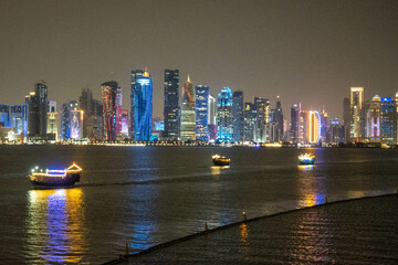Banner of capital city of Qatar by night. Doha West Bay skyline mirroring in Doha Bay. Panorama of glassed skyscrapers of Doha, Qatar, Middle East, Arabian Peninsula in Persian Gulf. Night urban scene