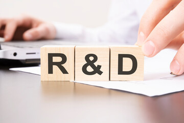 hand holding wooden cube with R and D text on table background. financial, marketing and business...