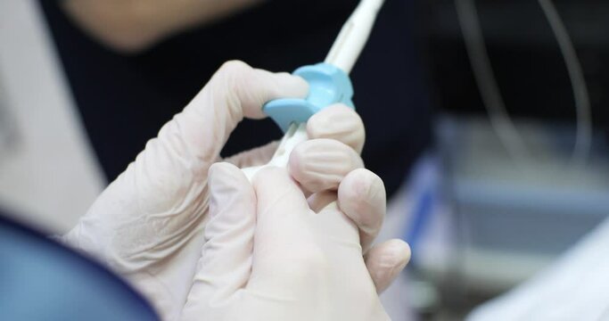 An assistant holds a biopsy equipment with his hand during an endoscopic examination. The control knob for the endoscopic biopsy probe lies in the assistant's hand.