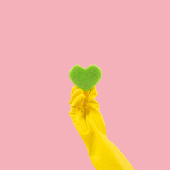 Heart shape green sponge and yellow rubber gloves on pink background. Minimal creative cleaning...