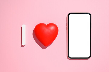 Red heart and smartphone with white empty display on pink background. Abstract inscription I love. The concept of congratulations on February 14