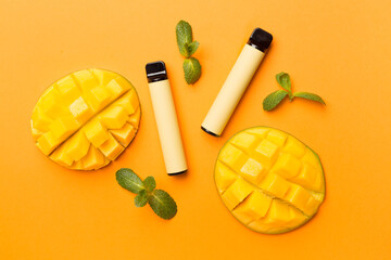 Disposable electronic cigarettes with mango fruit on color background, top view