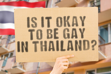 The question " Is it okay to be gay in Thailand? " is on a banner in men's hands with blurred background. Friendly. Passionate. Contact. Date. Dating. Lover. Partner. Boyfriend. Pleasant. Approval