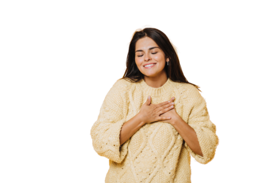Young pretty caucasian woman wearing a yellow jumper, laughing keeping hands on heart, concept of happiness. Cheerful hispanic girl toothy smiles eyes closed against transparent background.