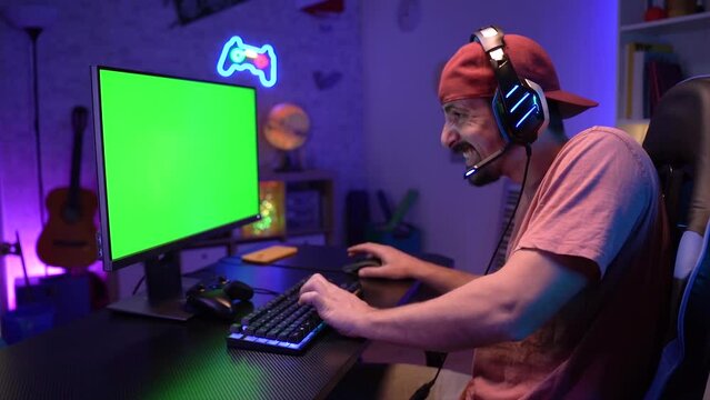 Gamer streaming and playing online video game on computer green screen colorful neon lights. High quality 4k footage
