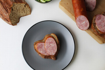 a sandwich with sausage heart on a gray plate view from above. Valentine's Day breakfast. Morning breakfast with coffee making a snack