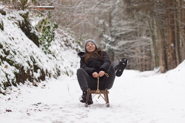 Winterzeit - Eine Frau fährt auf einem Schlitten schnell den Berg hinab