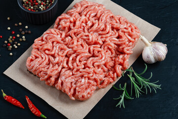 Fresh raw minced beef on backing paper and cutting board and ingredients