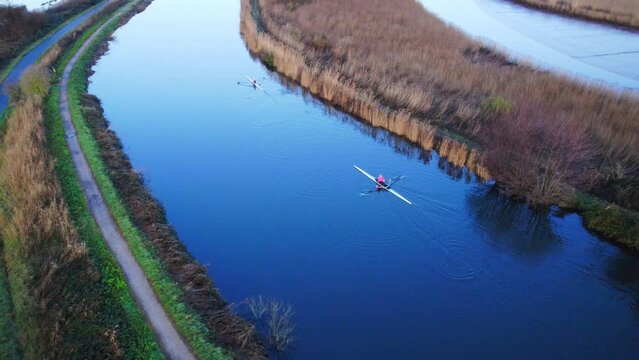 Aerial shot of person rowing along Exeter Ship canal and Topsham Lock in early morning light
