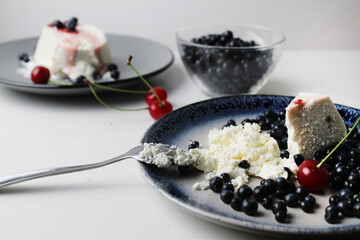 ricotta cheese with blueberries cherries on a plate close-up on a white background. Healthy food summer dessert. Cottage cheese dessert