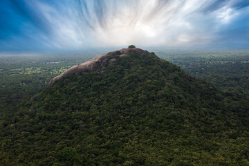 View from Sigiriya Sri Lanka to Pidurangala mountain. Path up the hill for tourists to climb the Lion Rock.  Sky with clouds.