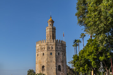 Obraz premium Golden Tower (Torre del Oro, from 13th century) located on the left bank of Guadalquivir River - historic military observation tower and Spanish cultural heritage monument. Seville, Andalusia, Spain.