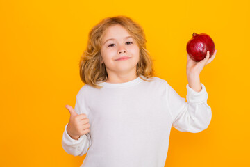 Kid hold red pomegranate in studio. Pomegranate fruit. Studio portrait of cute child with...