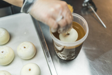 Top view of a person covering round doughnuts in caramel chocolate icing. Professional bakery. High...