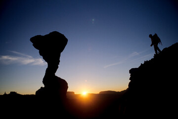 Hiker and sunset near the Cobra, a sandstone formation in the Fishers Towers, near Moab, Utah.
