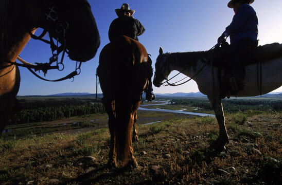 Three horse back riders in cowboy hats, Wyoming, USA.
