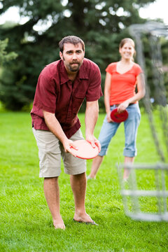 A man and woman play disk golf.