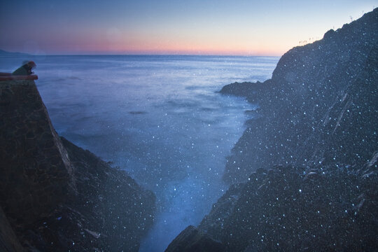 A tourist leans over the sea wall at twilight for a view of the La Bufadora blowhole in Baja California, Mexico.