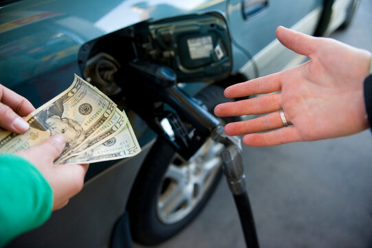 Close up of a young woman's hands, handing money for gasoline to the station attendant in Bend, Oregon.